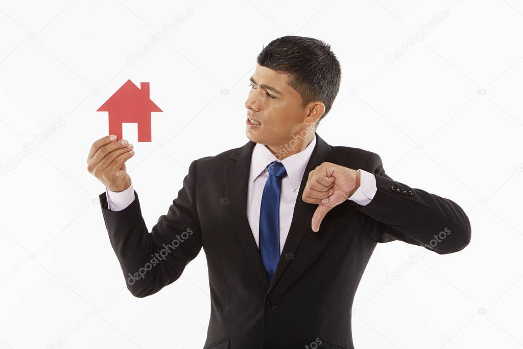Businessman holding up a cut out house, giving thumbs down