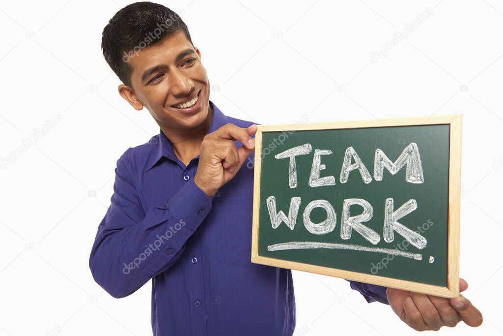 Businessman holding up a blackboard with 'Team work' written on it