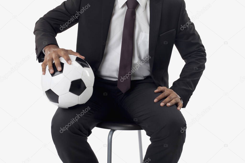 Soccer manager holding a ball on his lap