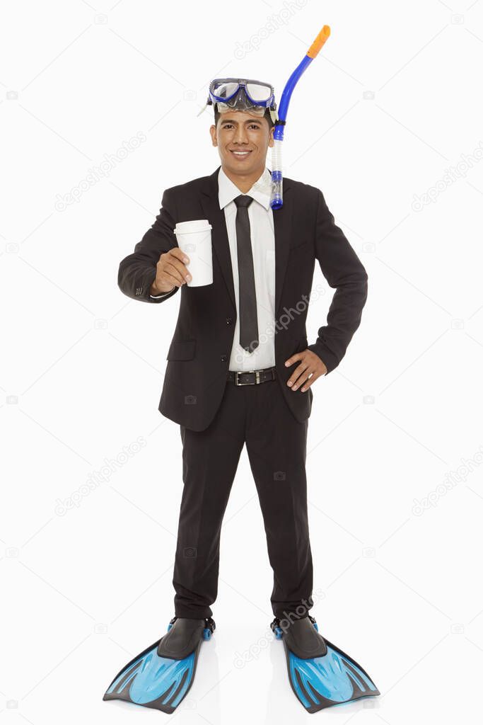 Businessman with swimming gear holding a disposable cup