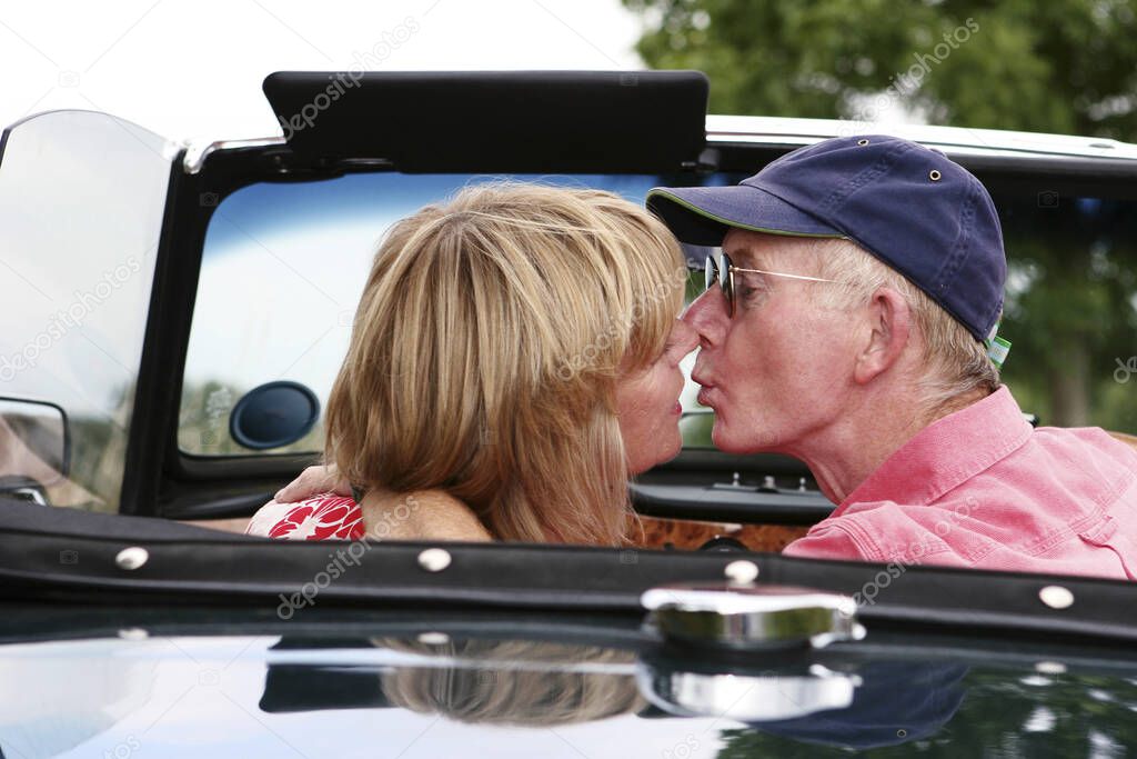 Back shot of a married couple kissing in the car
