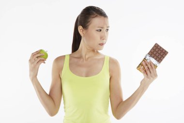 Elmayla çikolata arasında seçim yapan bir kadın.