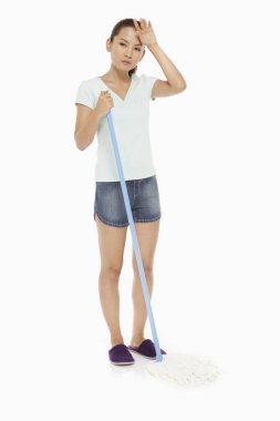 Yerleri silip alnına dokunan bir kadın.