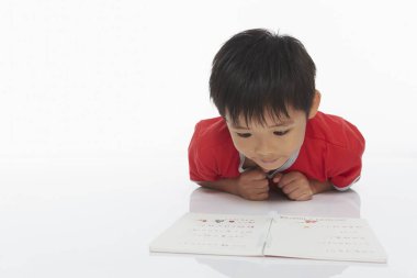 Önünde uzanmış, ders çalışıyor.