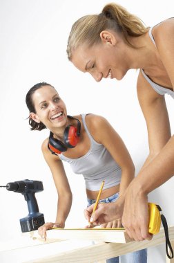 İki kadın bir odunu ölçerken gülüyordu.