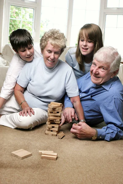 Pareja Ancianos Jugando Bloques Construcción Mientras Sus Nietos Observan — Foto de Stock