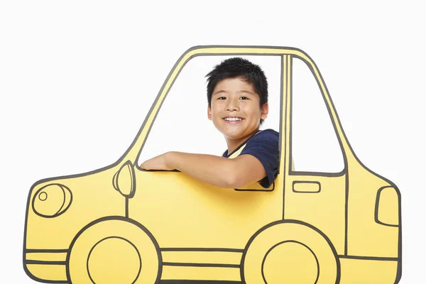 Boy looking out a cardboard car window, smiling