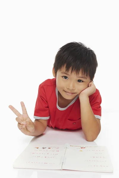 Junge Liegt Auf Seiner Vorderseite Und Zeigt Ein Friedenszeichen — Stockfoto