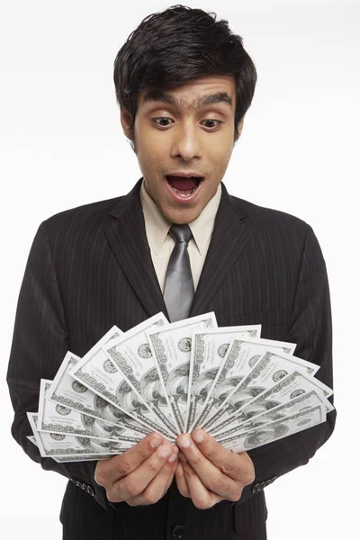 Biznesmen Trzyma Pieniądze Wyglądając Zaskoczonego — Zdjęcie stockowe