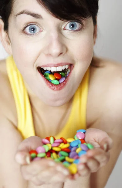 一握りのキャンディと口の中の女性 — ストック写真