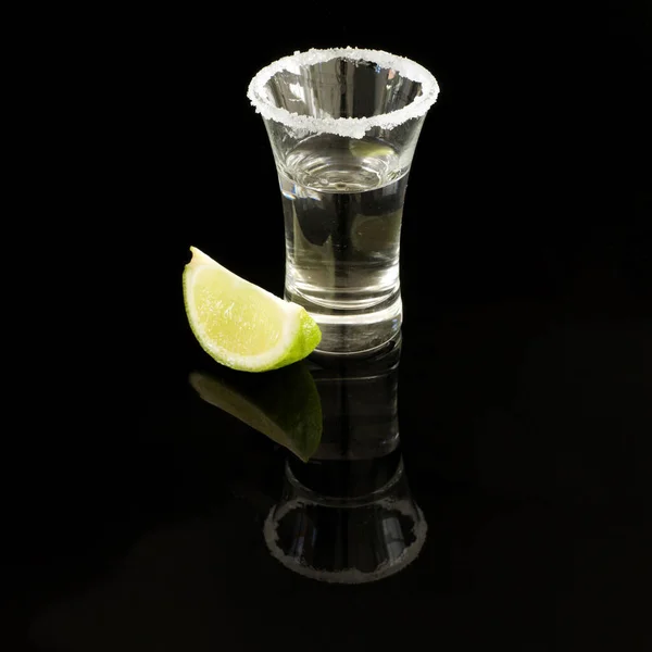 Shot of tequila with salt rimmed glass and wedge of lime