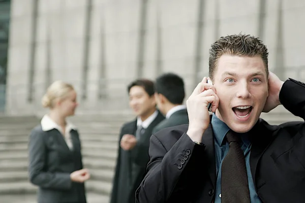 Hombre Emocionado Hablando Por Teléfono Mientras Sus Colegas Están Charlando — Foto de Stock