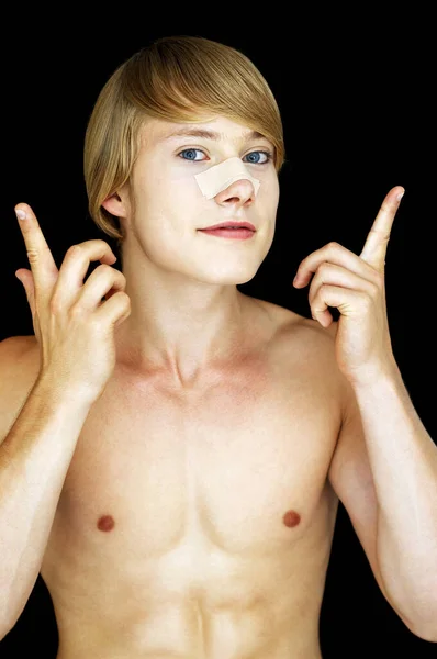 一个赤身裸体的男人把石膏贴在鼻梁上 — 图库照片