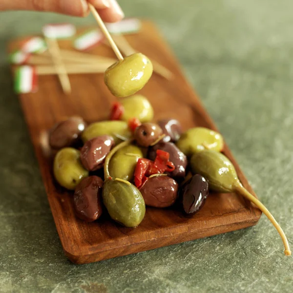 Hand taking fresh Italian olive with Italian flag pick from wooden plate — Stock Image Hand Taking Fresh Italian Olive Italian Flag Pick Wooden Plate Stock Photo
