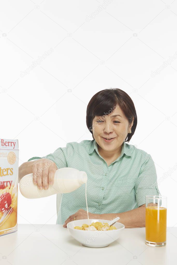 Cheerful woman pouring milk into a bowl of cereals