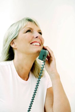 Telefonda konuşurken gülümseyen bir kadın.