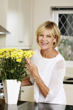 Vazoda çiçek düzenleyen yaşlı kadın.