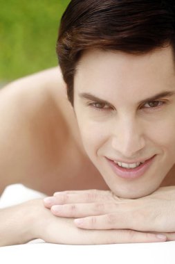 Masaj masasında yatan adam gülümsüyor.