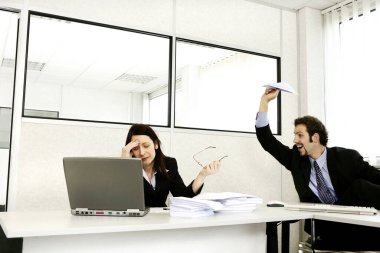 İş adamı stresli meslektaşına kağıt uçak fırlatıyor.