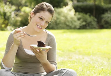 Çikolatalı pasta yiyen genç bir kadın.