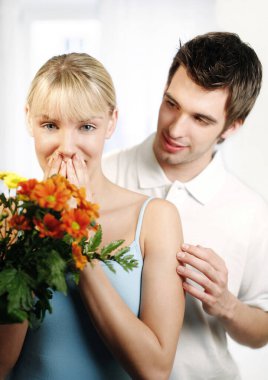 Kadın kocasından bir buket çiçek aldığına şaşırmış görünüyor.