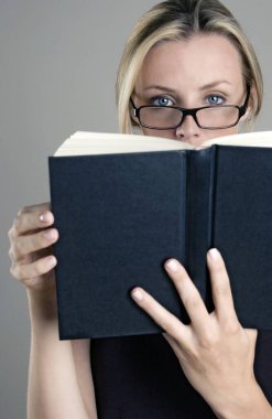 Kitap okuyan gözlüklü bir kadın.