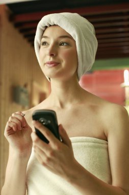 Havlu giymiş bir kadın cep telefonu kullanıyor.