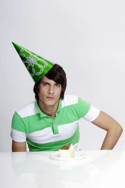 戴着派对帽 面前有一块蛋糕的男人 — 图库照片