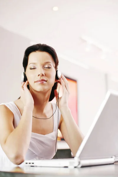 Frau Hört Musik Über Kopfhörer Während Sie Laptop Benutzt — Stockfoto