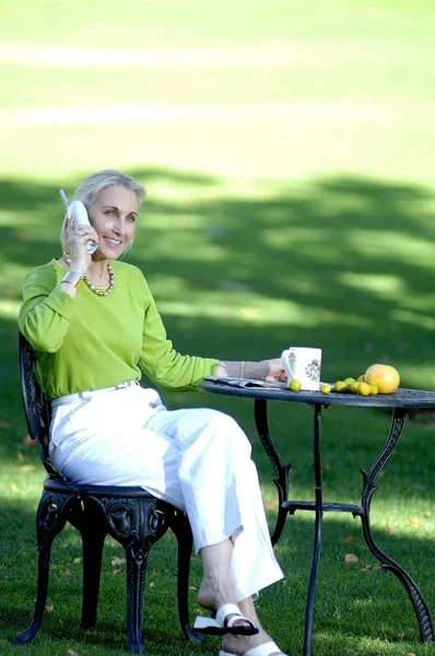 Bir Kadın Bahçede Kahve Içerken Telefonda Konuşuyor — Stok fotoğraf
