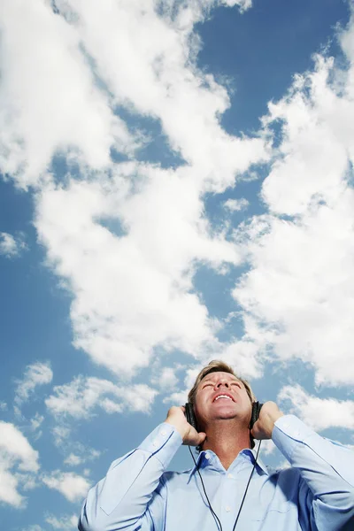 Man Met Koptelefoon Tegen Bewolkte Lucht — Stockfoto