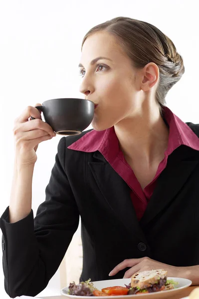 Businesswoman sipping coffee, studio shot