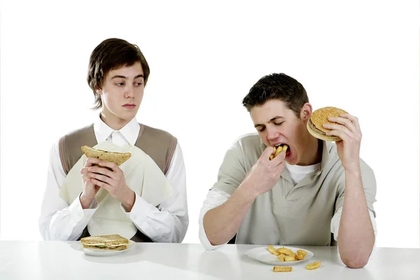 Man looking at his friend eating greedily