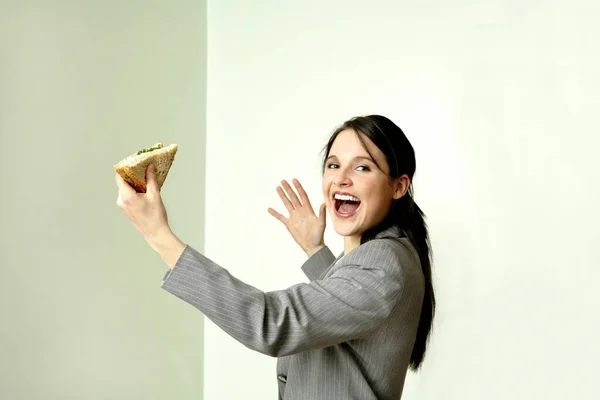 拿着三明治和蛋糕的年轻女人 — 图库照片