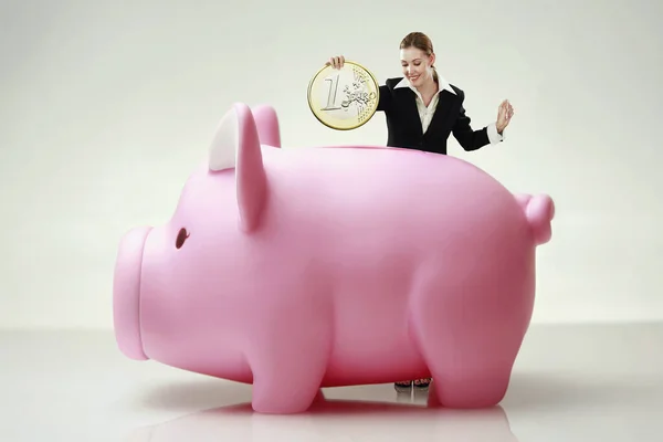 Businesswoman Putting Giant Sized Coin Piggy Bank Slot — Fotografia de Stock