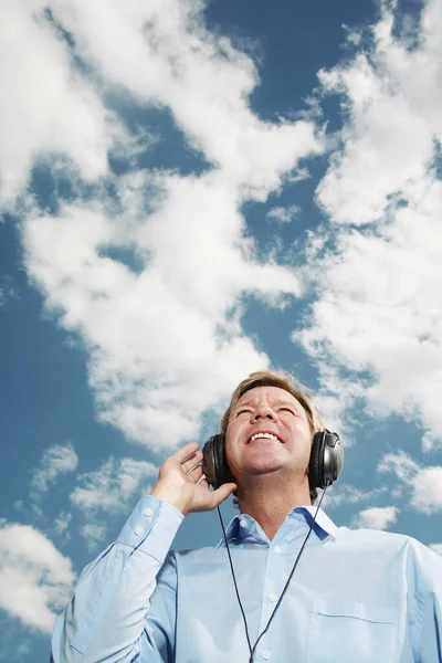 Man Met Koptelefoon Tegen Bewolkte Lucht — Stockfoto