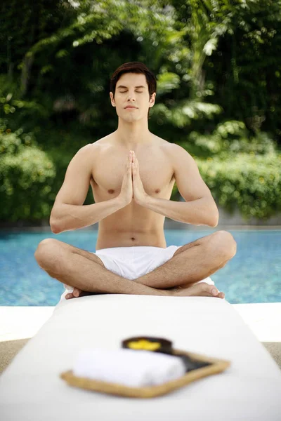 Man meditating by the swimming pool
