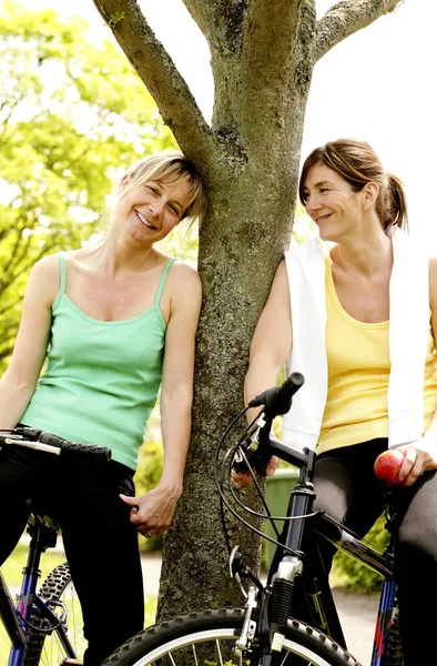 Två Kvinnor Ler När Sitter Cyklar — Stockfoto