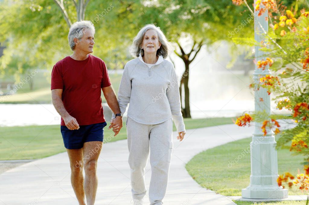 Old couple holding hands while walking in the park