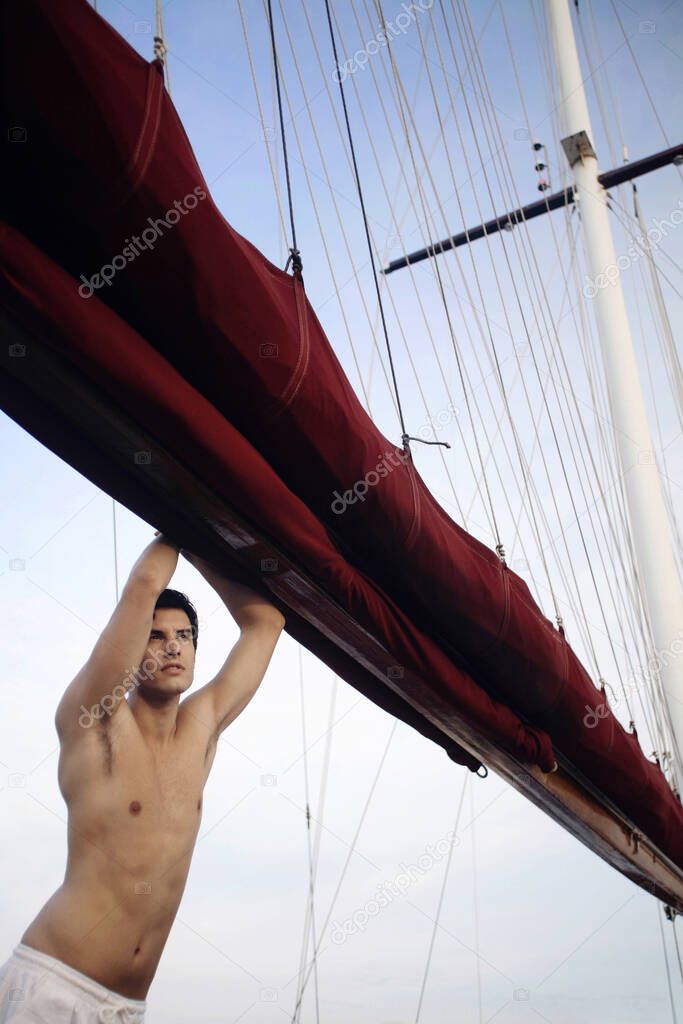 young man in red shirt posing on yacht