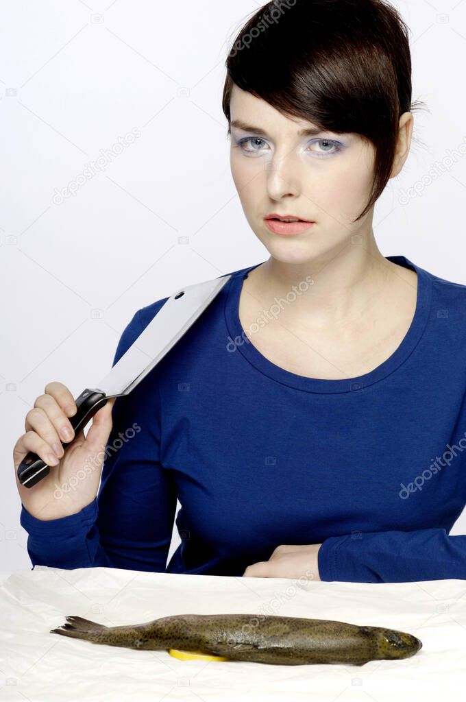 Woman holding a knife with fish on the table
