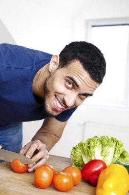 Adam mutfakta sebze doğruyor.