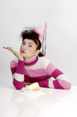 Parti şapkalı kadın pasta yiyor.