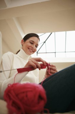 Kanepede oturan kadın örgü örüyor.