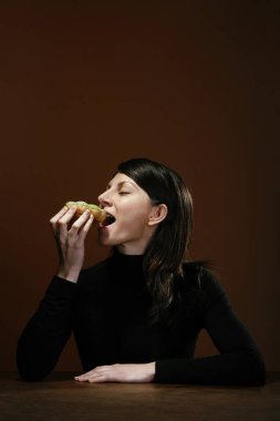 Genç bir kadın sandviç yiyor.