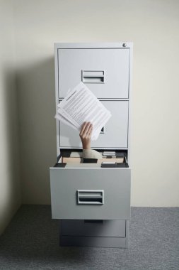 İş kadınının eli açık dolaptan çıkarken elinde kağıtlar vardı.