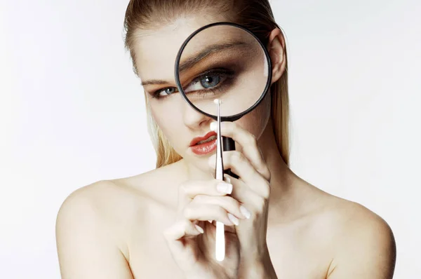 Woman looking at a tiny object with a magnifying glass