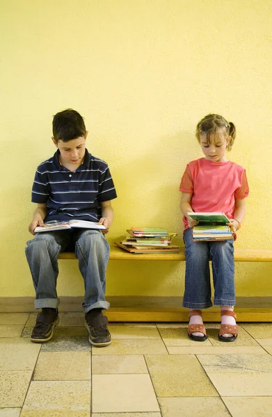 男の子と女の子座っているベンチで本を膝の上に — ストック写真