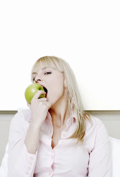 Businesswoman biting a green apple