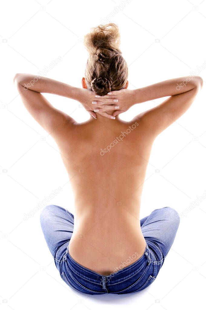 Back shot of a topless woman sitting on the floor